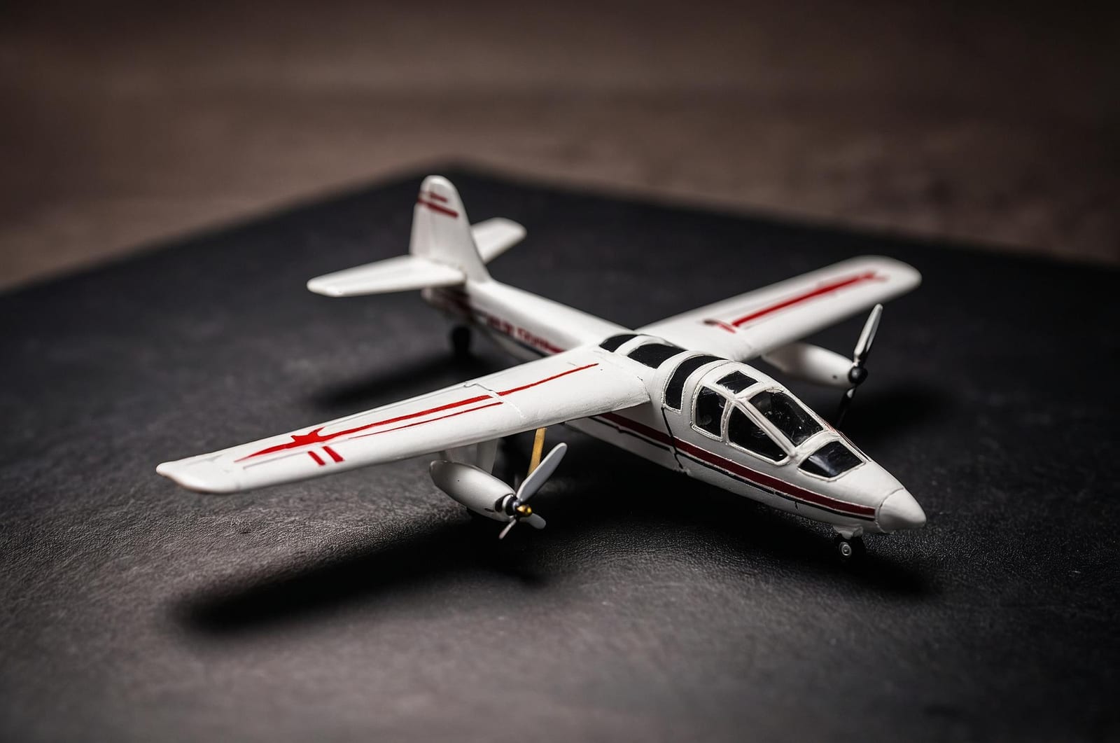Aeromodelo bimotor branco em exibição sobre uma superfície escura
