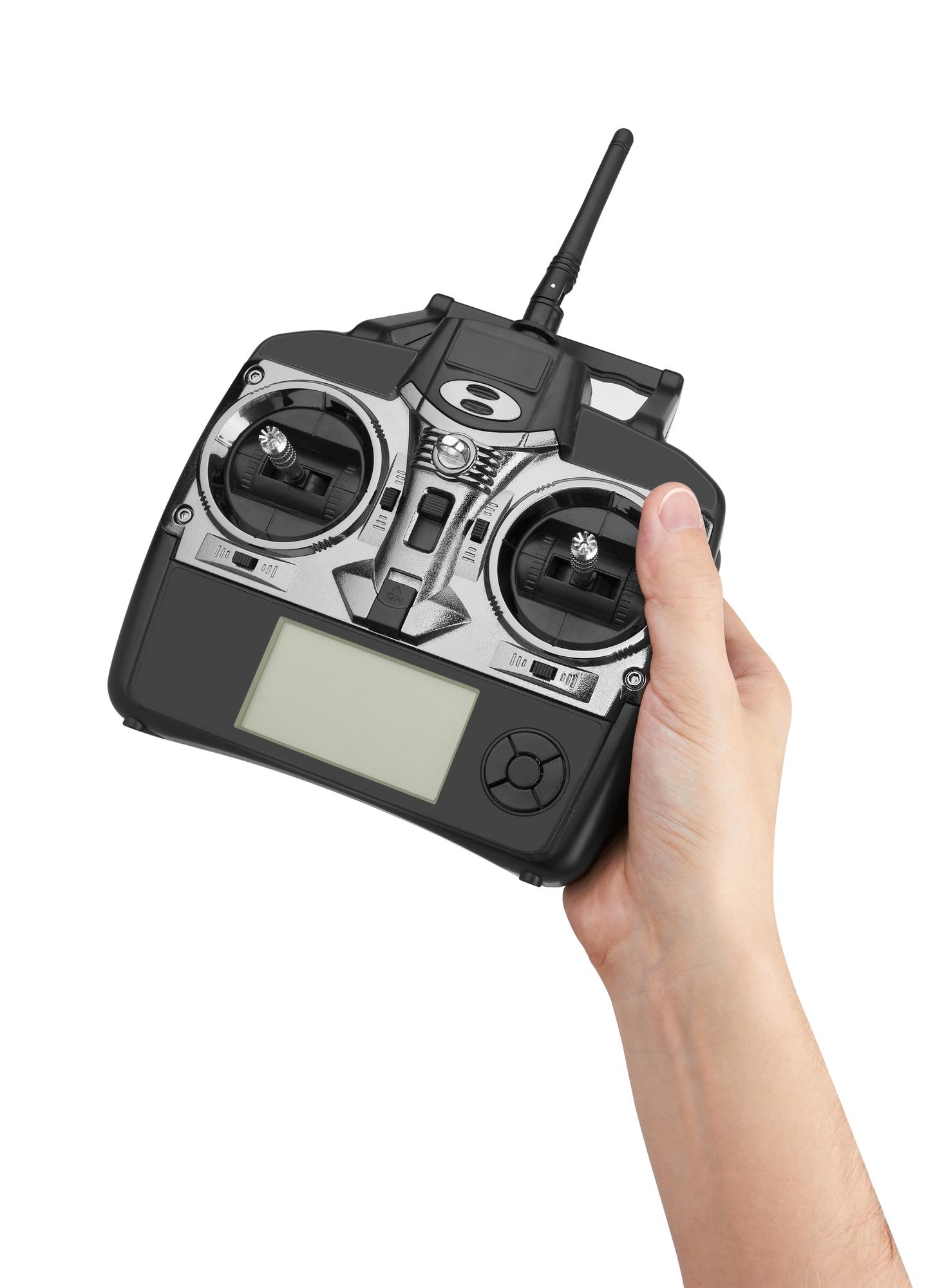 Mão segurando um rádio-controle preto com antena sobre fundo branco